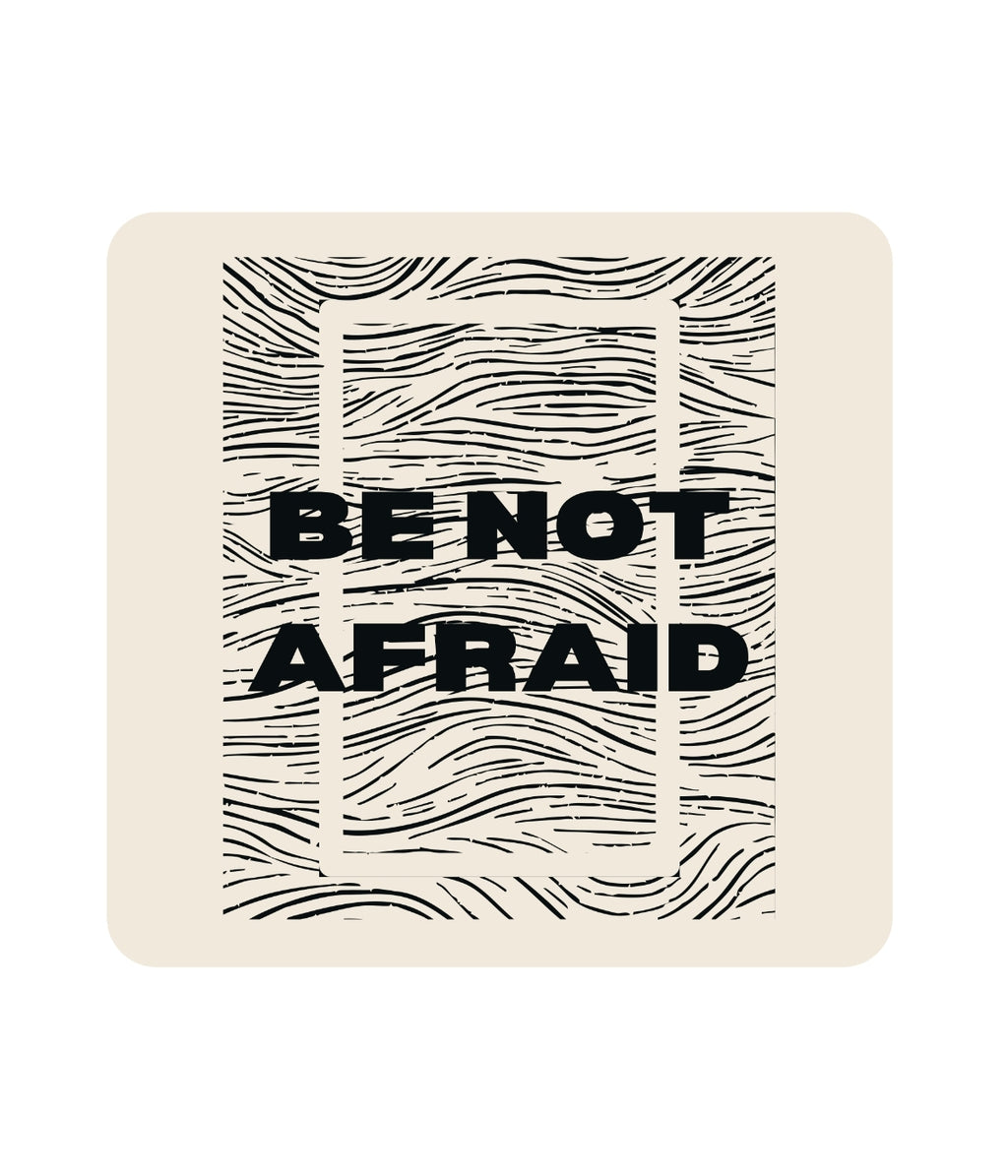 Beige coaster with black text 'BE NOT AFRAID' and wavy line design on a white background